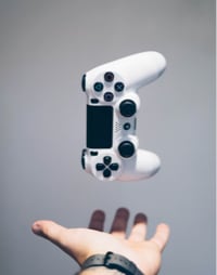 A ps4 controller thrown in the air with a hand beneath it